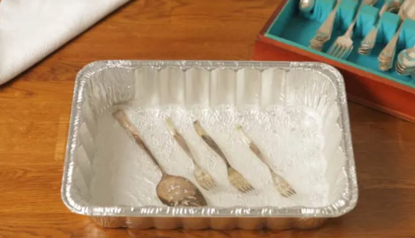 Cleaning silver with an aluminum baking pan, baking soda, salt, and boiling water.